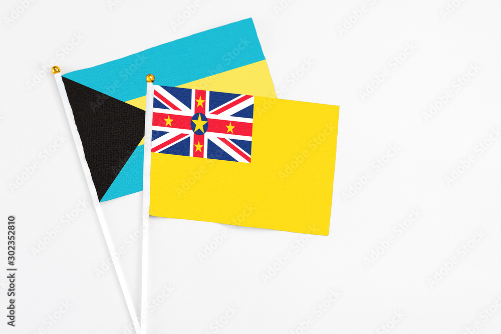 Niue and Bahamas stick flags on white background. High quality fabric, miniature national flag. Peaceful global concept.White floor for copy space. Niue and Bahamas stick flags on white background. High quality fabric, miniature national flag. Peaceful global concept.White floor for copy space.