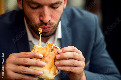 Businessman eating junk food sandwich 
