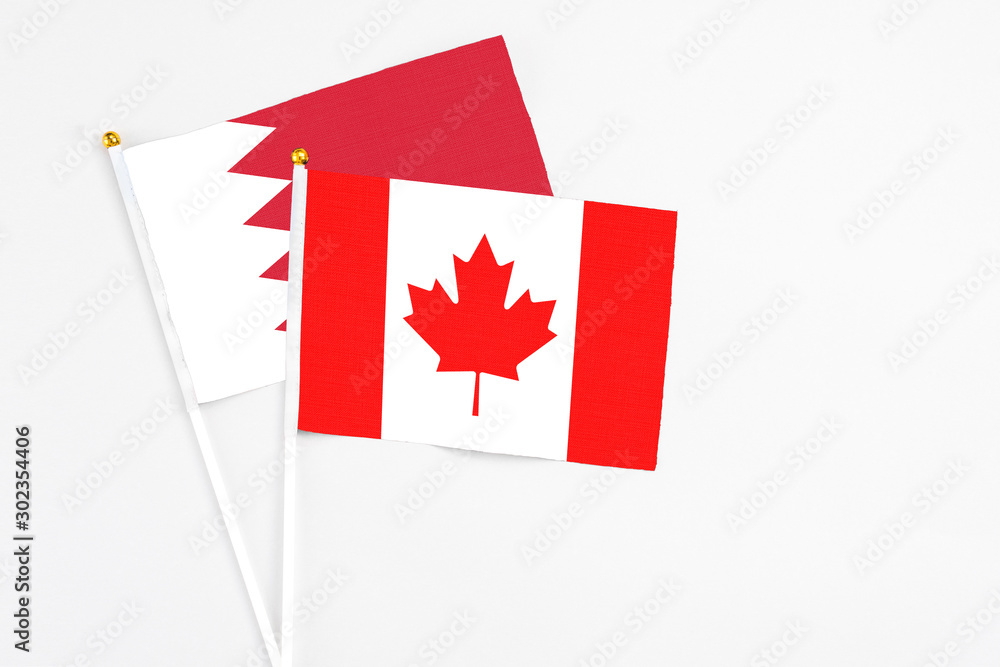 Obraz premium Canada and Bahrain stick flags on white background. High quality fabric, miniature national flag. Peaceful global concept.White floor for copy space.