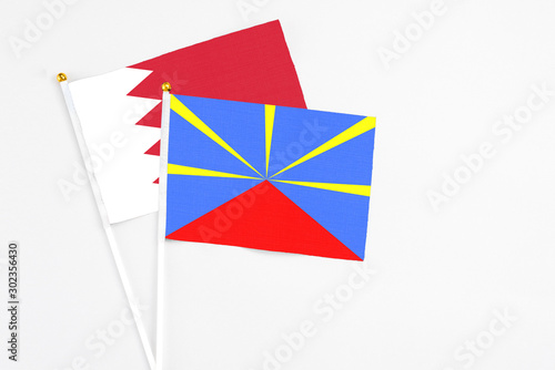 Reunion and Bahrain stick flags on white background. High quality fabric, miniature national flag. Peaceful global concept.White floor for copy space.