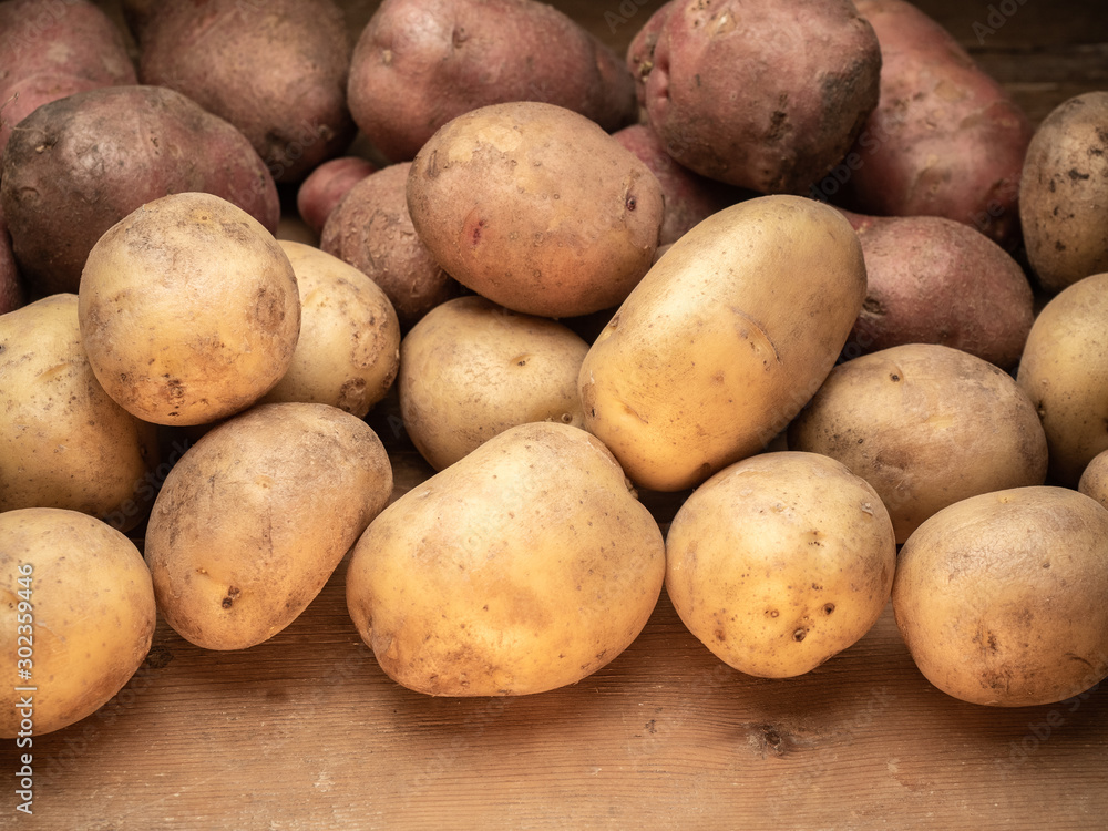 Rustic potatoes. Vegetables from farmhouse field is lying in bulk on wooden table from naturalplanks. Close up view on clean potatoes. Rustic potatoes. Vegetables from farmhouse field is lying in bulk on wooden table from naturalplanks. Close up view on clean potatoes.