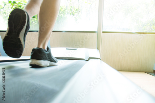Close-up of a man's foot in a sneakers running on a treadmill in a gym. Fitness concept.