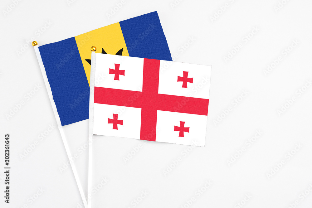Georgia and Barbados stick flags on white background. High quality fabric, miniature national flag. Peaceful global concept.White floor for copy space.
