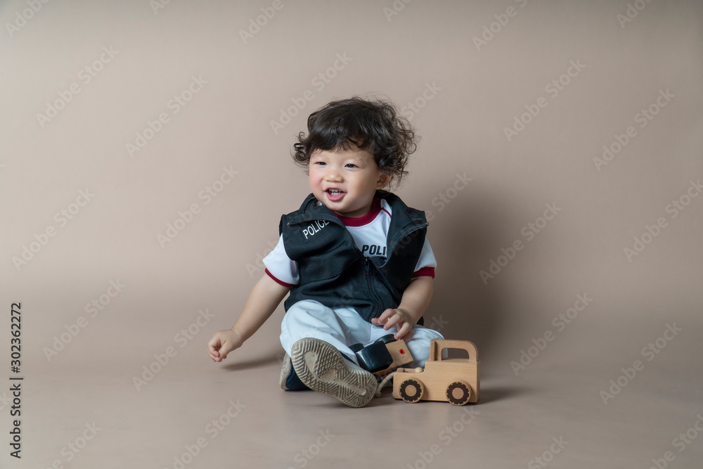 Asian kid playing with so toys on light brown background. Asian kid playing with so toys on light brown background.