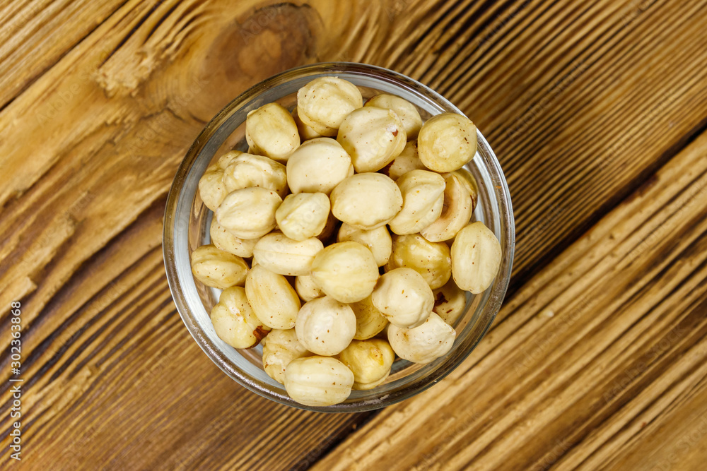 Peeled hazelnuts in glass bowl on wooden table. Top view Peeled hazelnuts in glass bowl on wooden table. Top view