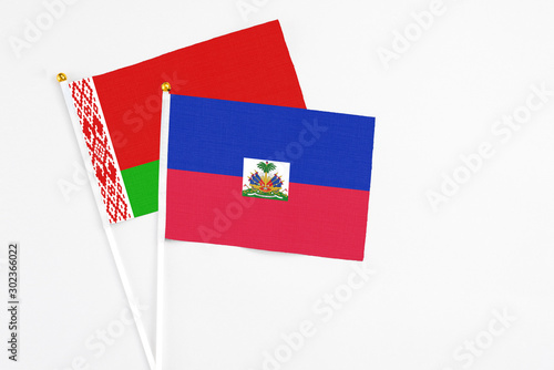 Haiti and Belarus stick flags on white background. High quality fabric, miniature national flag. Peaceful global concept.White floor for copy space. photo