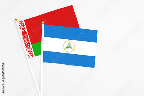 Nicaragua and Belarus stick flags on white background. High quality fabric, miniature national flag. Peaceful global concept.White floor for copy space. photo