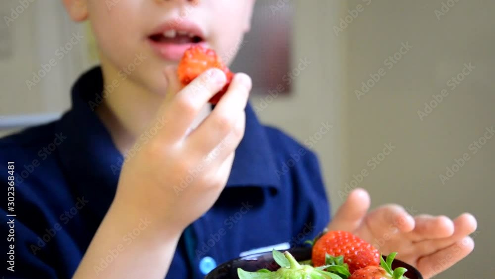 Happy children boy brother eating strawberries large red berries in the kitche Happy children boy brother eating strawberries large red berries in the kitche