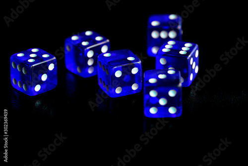 Blue dice scattered on a black surface close-up. Gambling background