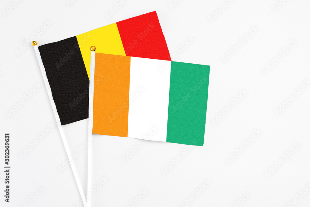 Cote D'Ivoire and Belgium stick flags on white background. High quality fabric, miniature national flag. Peaceful global concept.White floor for copy space. Cote D'Ivoire and Belgium stick flags on white background. High quality fabric, miniature national flag. Peaceful global concept.White floor for copy space.