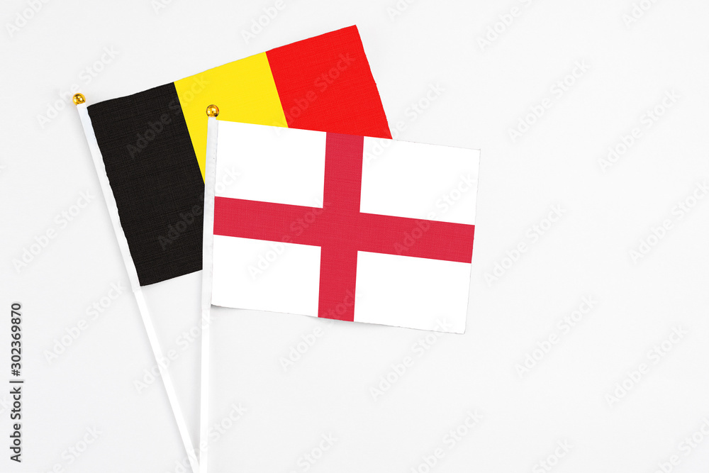 England and Belgium stick flags on white background. High quality fabric, miniature national flag. Peaceful global concept.White floor for copy space.