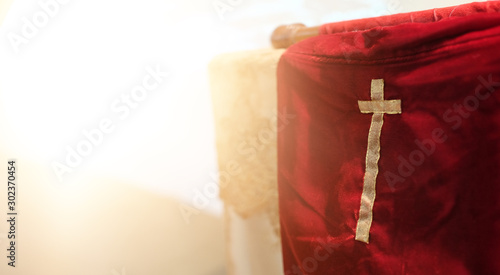 Foto Offering red fabric bag with gold cross in church with natural flare light, with