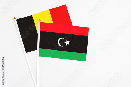 Libya and Belgium stick flags on white background. High quality fabric, miniature national flag. Peaceful global concept.White floor for copy space. photo