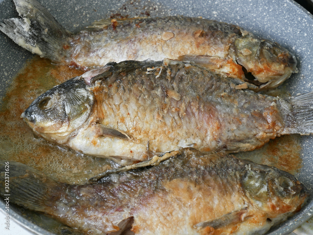 Three crucian fish are fried on a pan Three crucian fish are fried on a pan