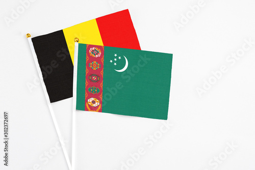 Turkmenistan and Belgium stick flags on white background. High quality fabric, miniature national flag. Peaceful global concept.White floor for copy space.