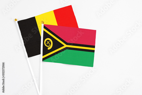 Vanuatu and Belgium stick flags on white background. High quality fabric, miniature national flag. Peaceful global concept.White floor for copy space.