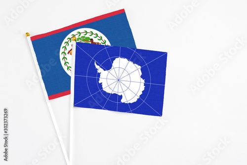 Antarctica and Belize stick flags on white background. High quality fabric, miniature national flag. Peaceful global concept.White floor for copy space.