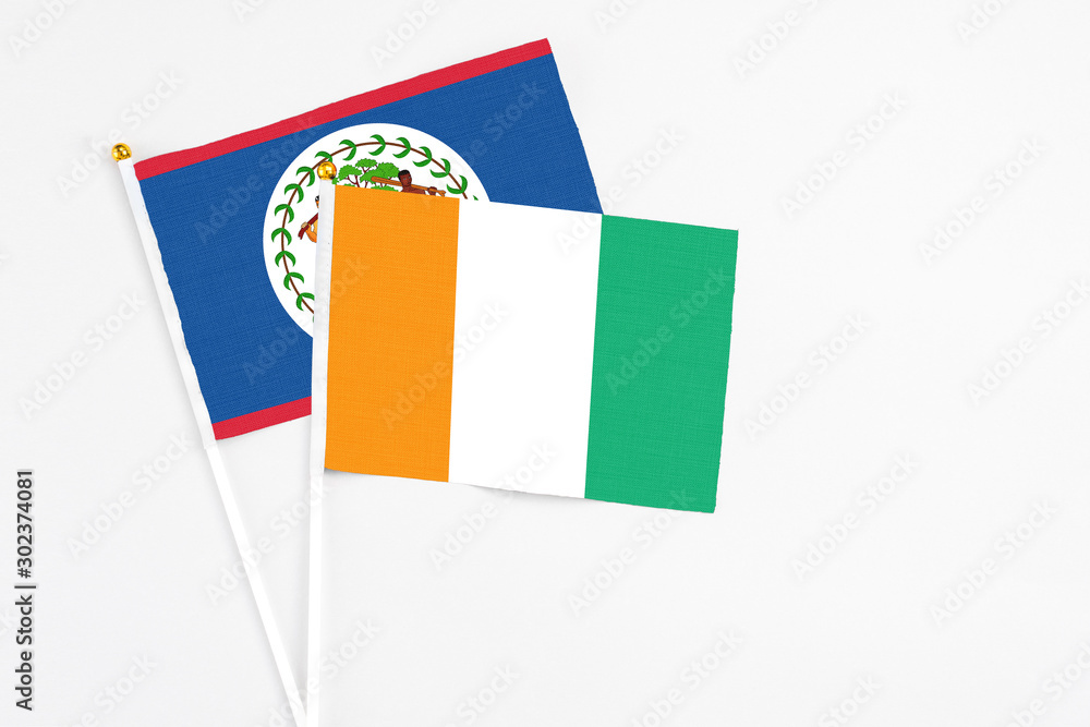 Cote D'Ivoire and Belize stick flags on white background. High quality fabric, miniature national flag. Peaceful global concept.White floor for copy space. Cote D'Ivoire and Belize stick flags on white background. High quality fabric, miniature national flag. Peaceful global concept.White floor for copy space.