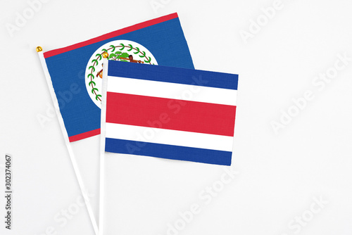 Costa Rica and Belize stick flags on white background. High quality fabric, miniature national flag. Peaceful global concept.White floor for copy space. photo