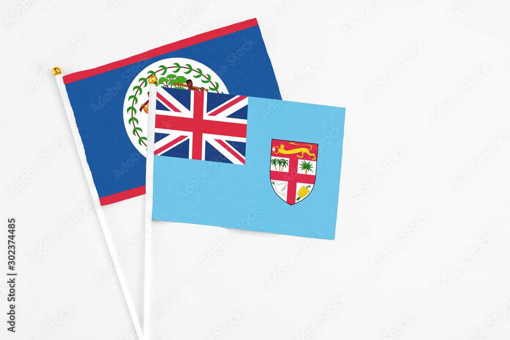 Fototapeta premium Fiji and Belize stick flags on white background. High quality fabric, miniature national flag. Peaceful global concept.White floor for copy space.