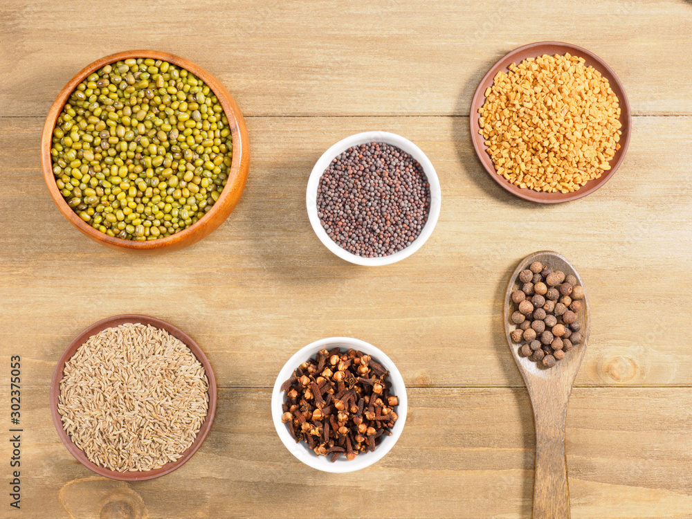 Allspice, mung bean, mustard seeds, fenugreek, cumin, cloves on brown wooden background. Indian cuisine, ayurveda, naturopathy, modern apothecary concept Allspice, mung bean, mustard seeds, fenugreek, cumin, cloves on brown wooden background. Indian cuisine, ayurveda, naturopathy, modern apothecary concept