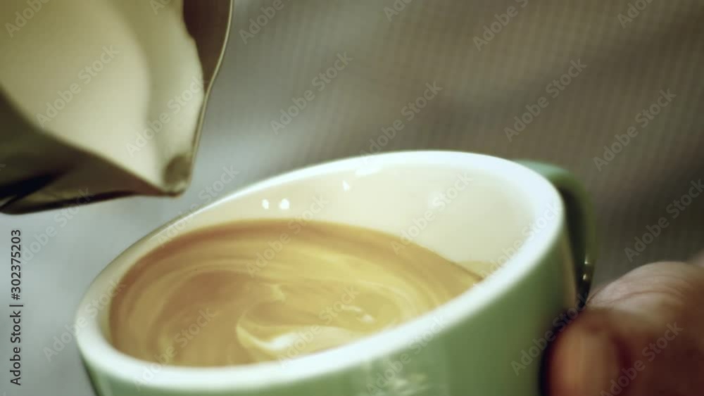 Barista prepares cappuccino in green mug Barista prepares cappuccino in green mug