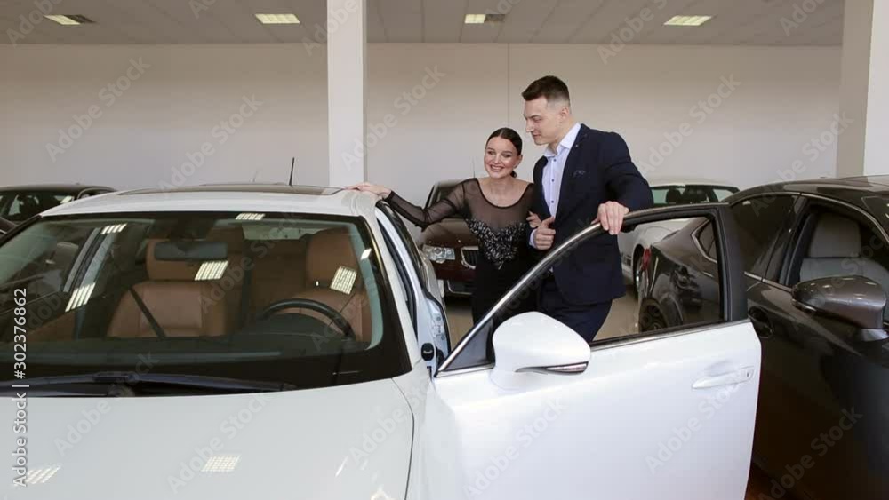 A young couple in love buys a car in the showroom. Buying or renting a car. Sale or rent a car. A young couple in love buys a car in the showroom. Buying or renting a car. Sale or rent a car.