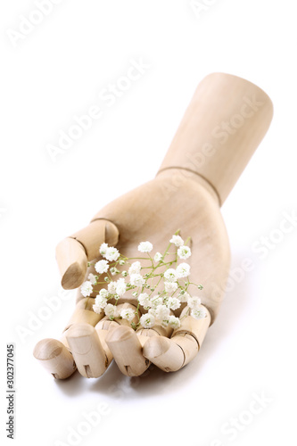 Single wooden hand holding tiny white flowers isolated on white