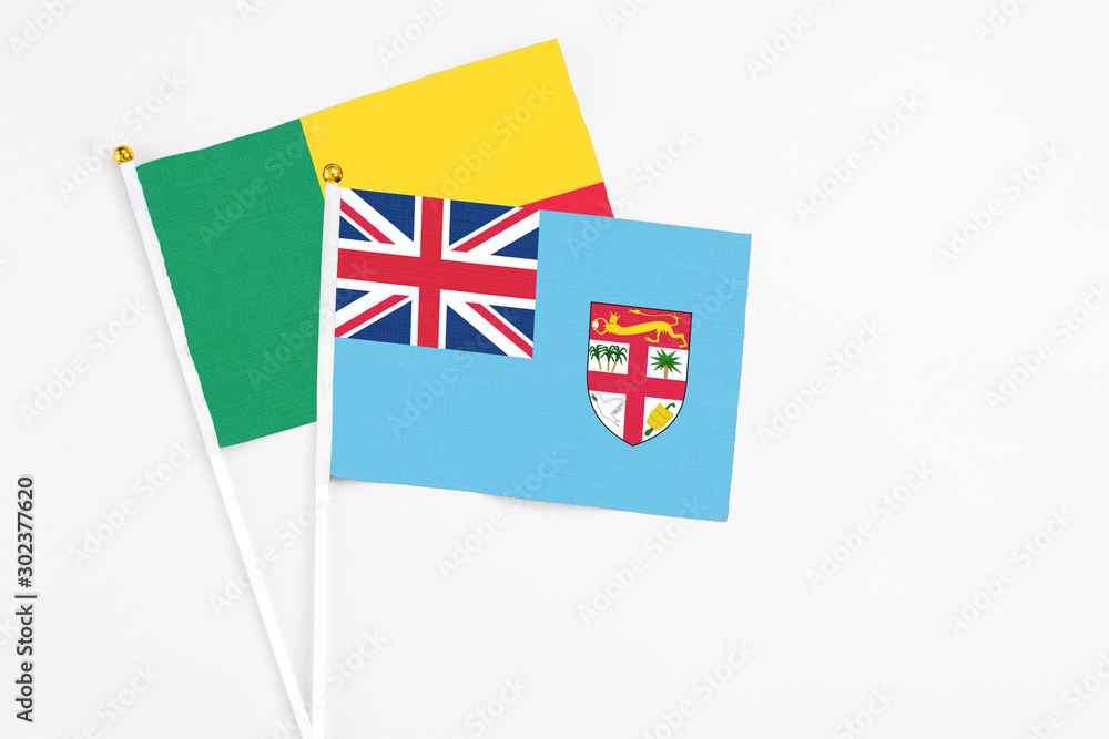 Fototapeta premium Fiji and Benin stick flags on white background. High quality fabric, miniature national flag. Peaceful global concept.White floor for copy space.