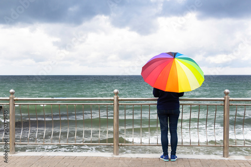 Young beautiful woman with colorful umbrella in the rain on the background of the sea or ocean © mihail39