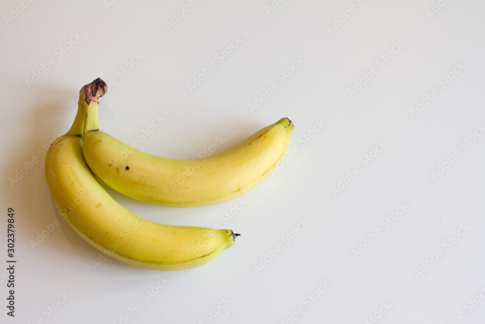 ripe yellow banana on white background. two bananas are on the table. space for text. the view from the top. ripe yellow banana on white background. two bananas are on the table. space for text. the view from the top.