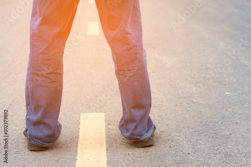 Standing Man Jeans on the asphalt road with path and sunlight, Behind view.
