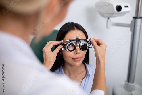 Dark-eyed woman sitting while having vision control in the morning