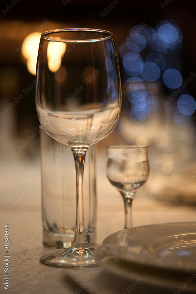 Empty glass glasses and glasses standing on a served table photographed with shallow depth of field against a background of blue bokeh circles