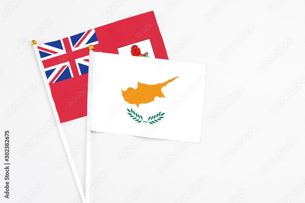 Obraz premium Cyprus and Bermuda stick flags on white background. High quality fabric, miniature national flag. Peaceful global concept.White floor for copy space.