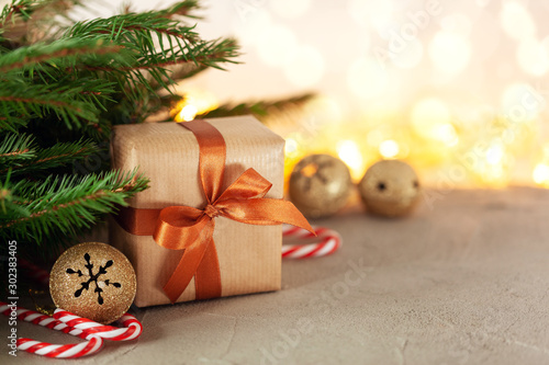 Christmas gift or present box wrapped craft with fir branches and holiday decoration on light bokeh background photo