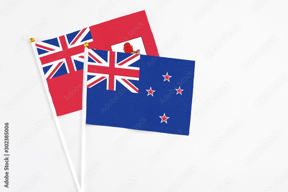 Fototapeta premium New Zealand and Bermuda stick flags on white background. High quality fabric, miniature national flag. Peaceful global concept.White floor for copy space.