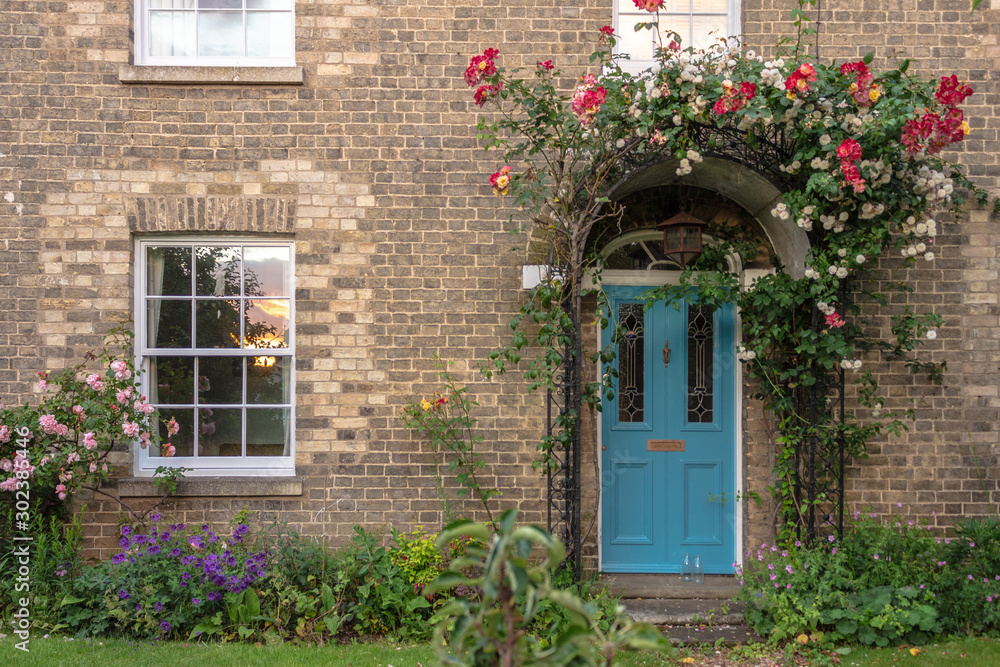 brick wall with cyan door and windows and climber overgrown plant with small garden facade brick wall with cyan door and windows and climber overgrown plant with small garden facade