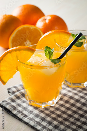 Photo of fresh orange juice in the glass jar. Summer healthy organic drink concept. Cold beverages with ice and orange fruits.