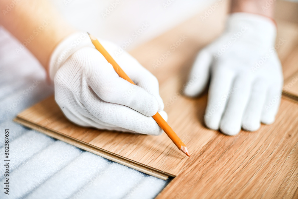 Close up of wood worker with in white gloves measuring tape and new laminated wooden floor board. - obrazy, fototapety, plakaty 