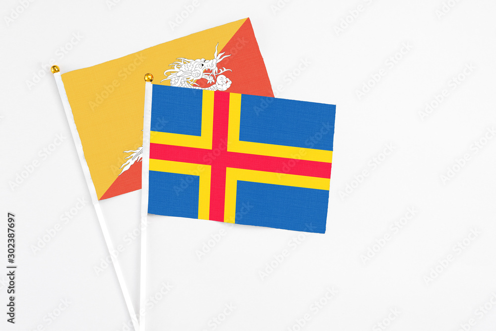 Aland Islands and Bhutan stick flags on white background. High quality fabric, miniature national flag. Peaceful global concept.White floor for copy space.