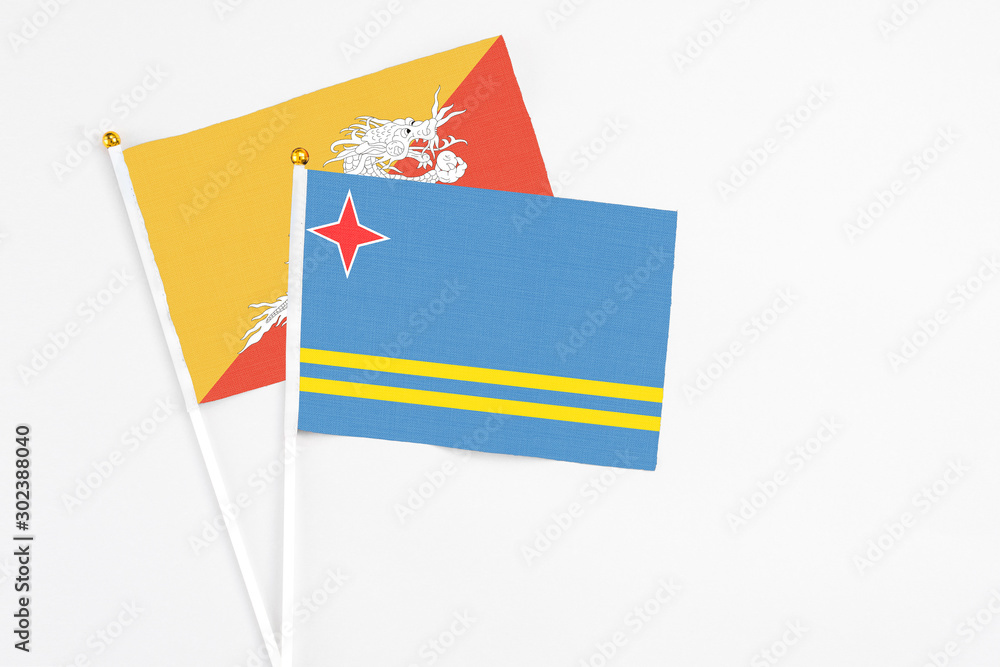 Aruba and Bhutan stick flags on white background. High quality fabric, miniature national flag. Peaceful global concept.White floor for copy space.