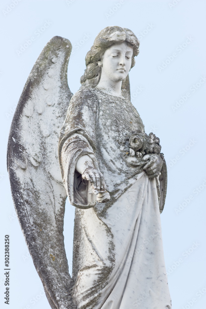 close up image of an angel figurine against a pale sky background.