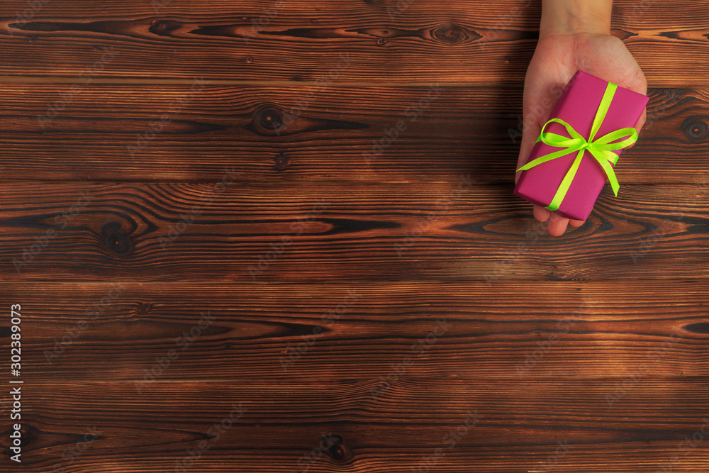 gift in female hands on a wooden background top view. - Image