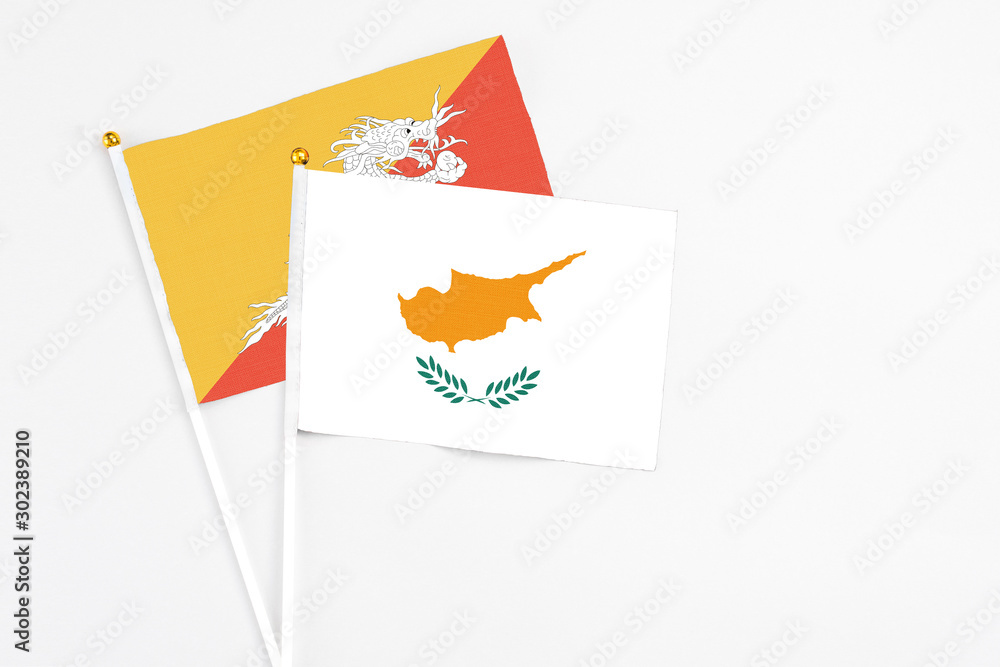 Obraz premium Cyprus and Bhutan stick flags on white background. High quality fabric, miniature national flag. Peaceful global concept.White floor for copy space.