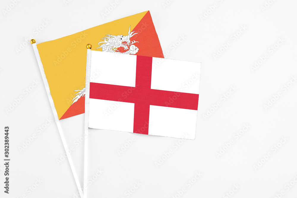 England and Bhutan stick flags on white background. High quality fabric, miniature national flag. Peaceful global concept.White floor for copy space.