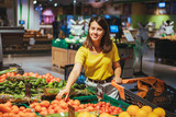 woman choosing red tomatoes from store shelf grocery shopping