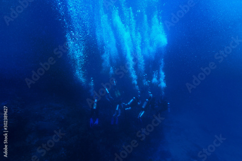 scuba divers in the deep blue ocean