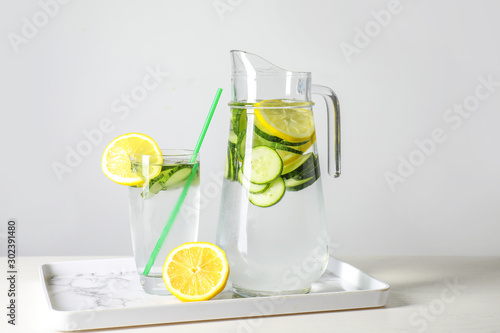 Jug and glass of healthy infused water on table