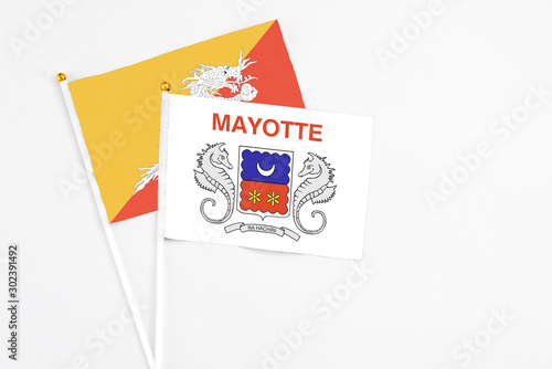 Mayotte and Bhutan stick flags on white background. High quality fabric, miniature national flag. Peaceful global concept.White floor for copy space.